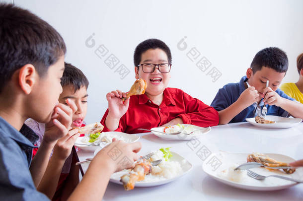 亚洲小男孩在学校食堂与朋友共进午餐时微笑着