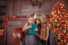 圣诞快乐，节日快乐 ！妈妈和女儿装饰在室内圣诞树。在圣诞节前早上。肖像充满爱的家庭关闭.