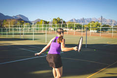 在明亮的阳光下, 关闭一个女网球运动员在球场上打网球的照片