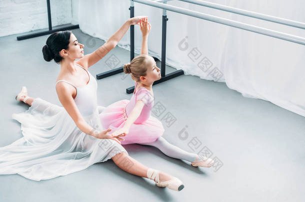 粉红色芭蕾舞短裙中可爱儿童的高角度观与教师在芭蕾学校的练习