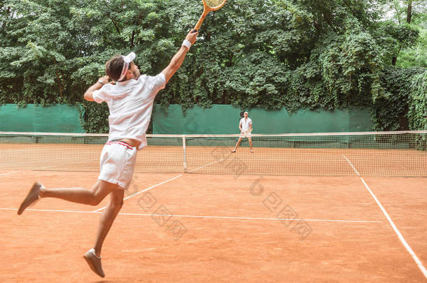 运动员在球场上与朋友打网球时跳跃