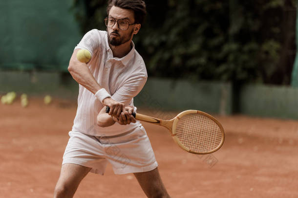 英俊的复古式网球运动员打球在网球场