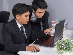 两名商务男士使用笔记本电脑讨论项目
