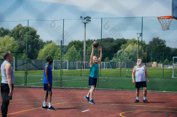 跨种族的老年运动员在操场上一起打<strong>篮球</strong>