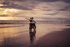 沙滩上的情侣骑摩托车后视图 