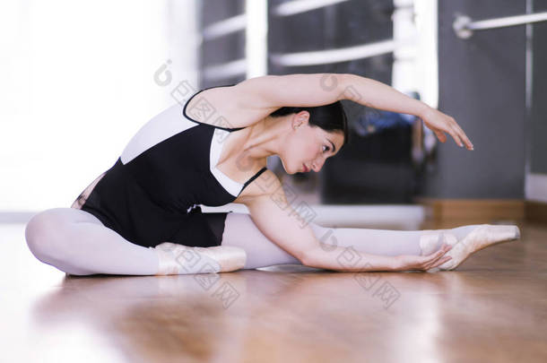 芭蕾舞演员坐在地板上伸展双手