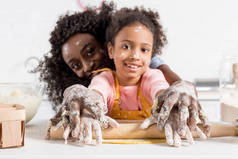 非洲裔美国人母亲和微笑的女儿滚面团与滚动别针一起在厨房