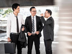 一组商务同事在会议咖啡歇期间聊天。亚洲商界男士站在办公楼前聊天.