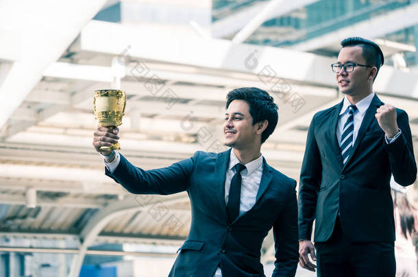 快乐的亚洲商界人士与<strong>金奖</strong>杯杯为他们的赢家在商业项目。团队合作和成功理念