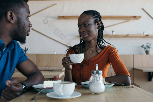 坐在桌边的非洲裔美国人夫妇咖啡和甜点在咖啡馆里