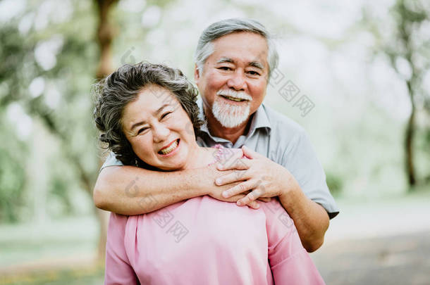 愉快的微笑高级亚洲情侣享受在公园的美<strong>好时光</strong>。一个男人紧紧拥抱女人。成功婚姻生活.