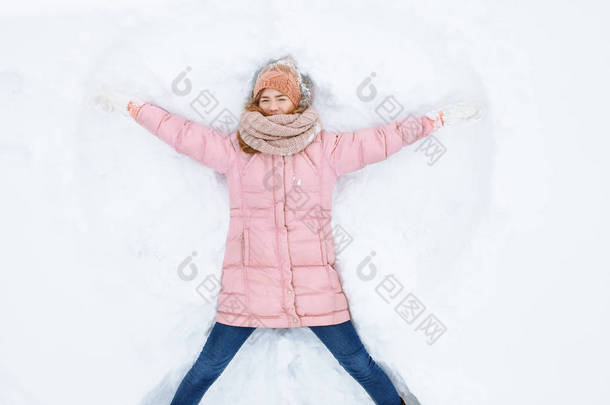 快乐的女人躺在雪地里, 胳膊和腿上下移动, 创造了一个雪天使的形状。微笑的妇女躺在雪地上的寒假, 为广告 ,