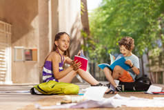 愉快的男孩和女孩与课本在学校附近读谈话微笑