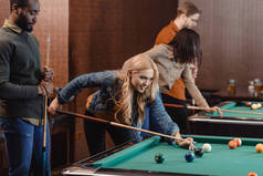 年轻迷人的多元朋友在酒吧玩台球