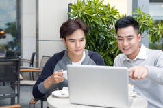 英俊的亚洲业务的同事或一起使用的笔记本电脑、 启动项目会议或团队集体概念，在咖啡厅或现代办公的高校学生工作