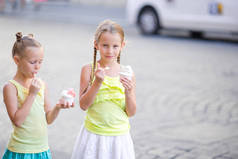 快乐的小女孩吃冰乳膏的露天咖啡馆。人、 孩子、 朋友和友谊的概念