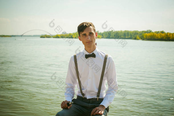 年轻的瘦男人，优雅时髦穿着白衬衫，裤子用<strong>吊带</strong>和领结