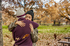 肖像年轻夫妇拥抱在雨中的树叶在秋天。Bac