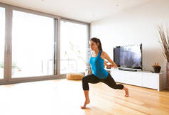 年轻的女人在家里做运动，拉伸胳膊和腿.