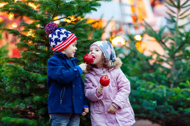 两个小孩子吃结晶的苹果上圣诞市场