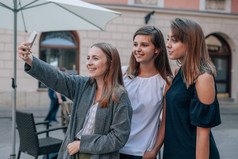 三个女孩正在用手机拍照。城市背景