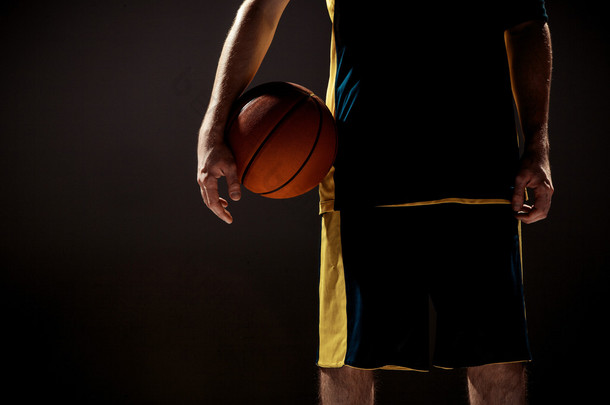 一名拿着篮子球在黑色背景上的篮球运动员的剪影视图