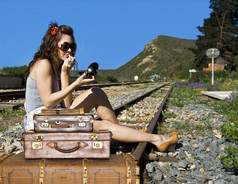 她在铁路轨道上的行李箱的年轻旅行女人