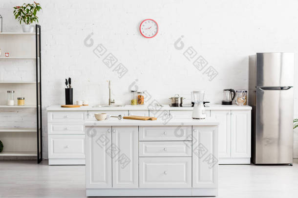 现代化的白色厨房, 配有<strong>桌子</strong>、厨具和冰箱 