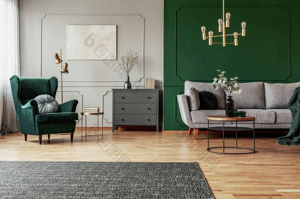 翡翠绿色翼椅，带枕头，灰色客厅内部带木制装饰
