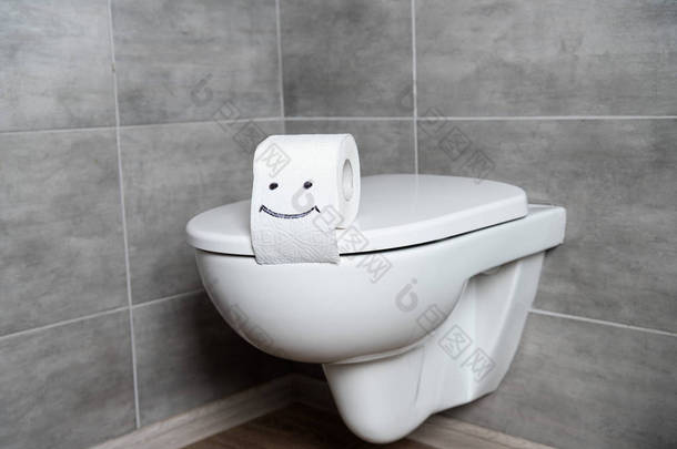 灰色瓷砖浴室白色马桶座卫生纸上的微笑标志