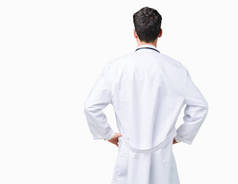 年轻的医生男子穿着医院外套在孤立的背景站向后看着你的手臂在身体
