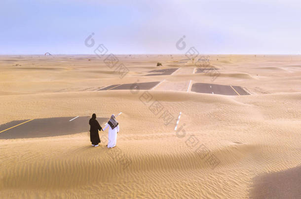 阿联酋夫妇在一个沙子覆盖的道路在沙漠附近的迪拜