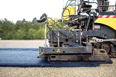工业路面卡车在建筑工地上的新鲜柏油铺设沥青