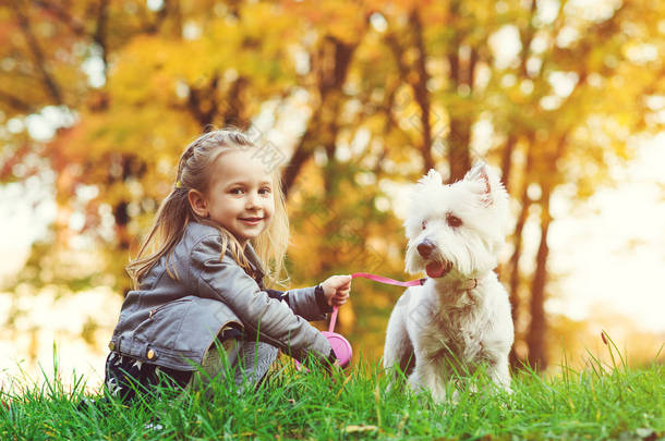 秋天公园里有狗的<strong>小女孩</strong>。可爱的<strong>微笑</strong>的<strong>女孩</strong>与她的宠物散步乐趣。快乐的孩子与狗在户外休息。秋天。快乐童年