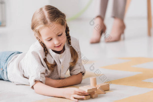 小孩在地板上玩木块与模糊的心理学家坐在背景