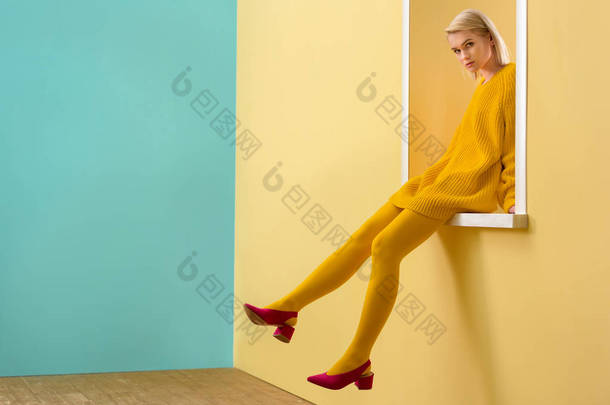 穿着<strong>粉红</strong>色鞋子, 黄色毛衣和紧身衣的<strong>时尚</strong>女人侧面观看装饰窗口