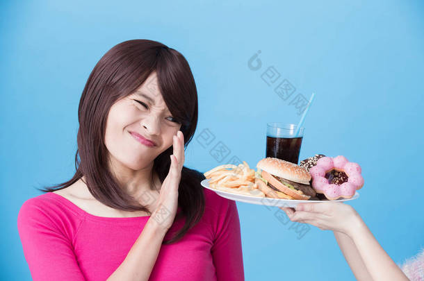 妇女拒绝不健康的食物在蓝色背景