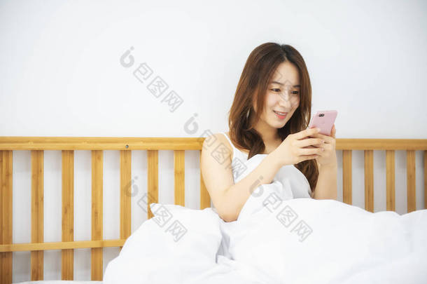 妇女在床上使用移动电话