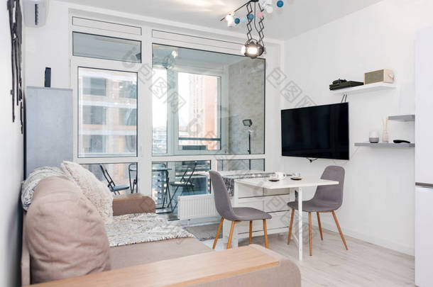 简约主义现代客厅，沙发轻盈简约主义风格的公寓。 带有厨房和客厅的现代阁楼，带有家具的斯堪的纳维亚风格的<strong>开放空间</strong>内部。 真正的照片
