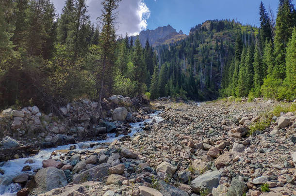 哈萨克斯坦的天山山脉的跨伊犁阿拉托山脉靠近阿拉木图市。夏中云层下覆盖着雪和冰川的落基山峰