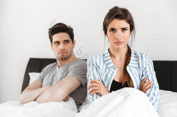 失望的年轻夫妇有冲突, 而坐在床上