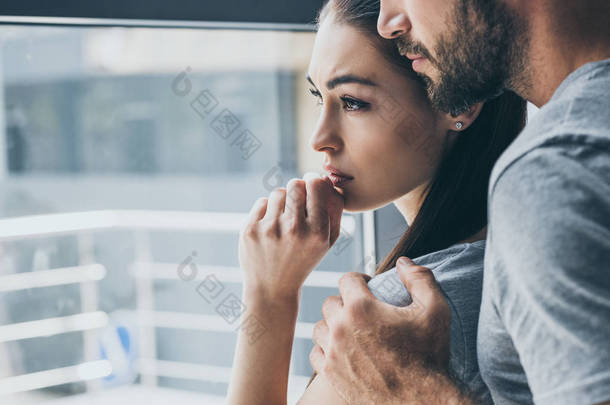 修剪照片的胡子男子支持悲伤的年轻女子看窗口