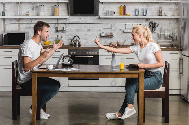青年夫妇在厨房早餐时吵架的侧面视图 