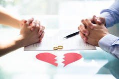 夫妇的手在离婚纸用结婚戒指和残破的心脏