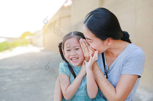 快乐的妈妈对她的小女儿耳语着一个秘密。<strong>母亲</strong>和孩子的沟通理念.
