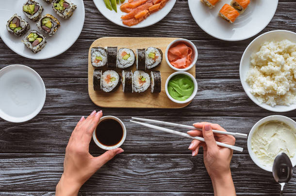 手持筷子和吃美味寿司的人被裁掉的镜头