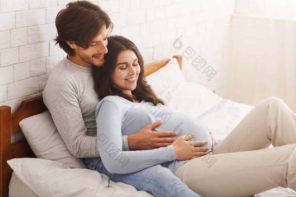 年轻的孕妇和丈夫躺在<strong>床</strong>上