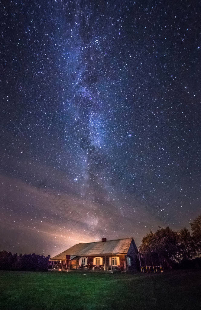 夜景观与五颜六色的银河明星在树木和城市外的家庭。夏天的星空和家在一起。美丽的宇宙。空间天文摄影背景