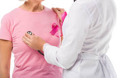 医生用听诊器检查乳房癌患者的健康状况与乳腺癌的认识丝带隔离在白色