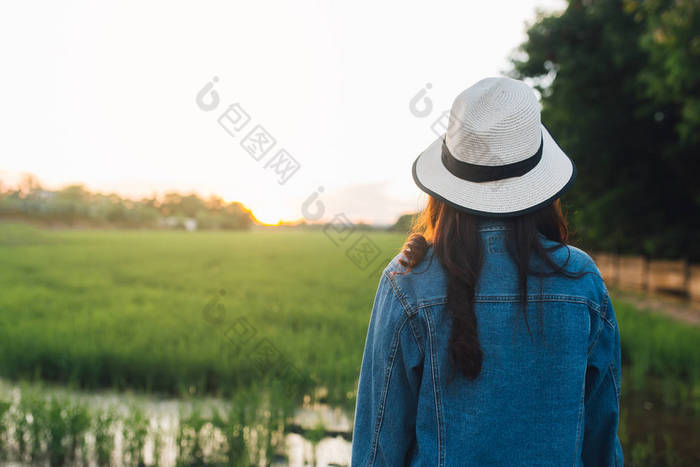 后面的年轻女子戴帽子。女孩享受美丽的自然与日落。旅游暑假假期与休闲理念.